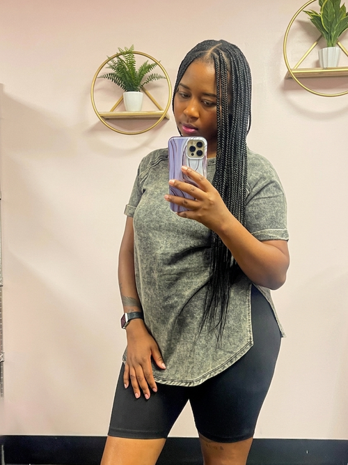Woman taking a mirror selfie wearing a mineral washed black oversized shirt and black shorts indoors.